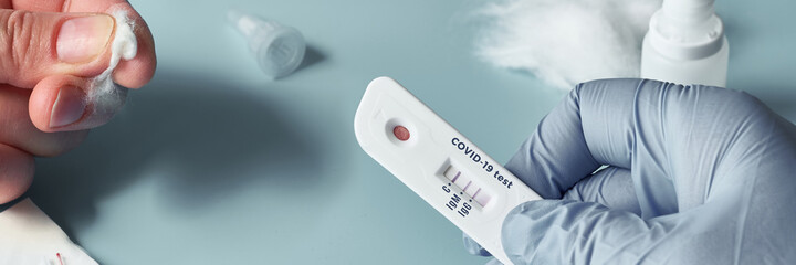 Express COVID-19 test for IgM and IgG antibodies to novel coronavirus SARS-CoV-2, Covid-19. Nurse hand in glove with positive test. Patient fingers with cotton. Bold turquoise background.