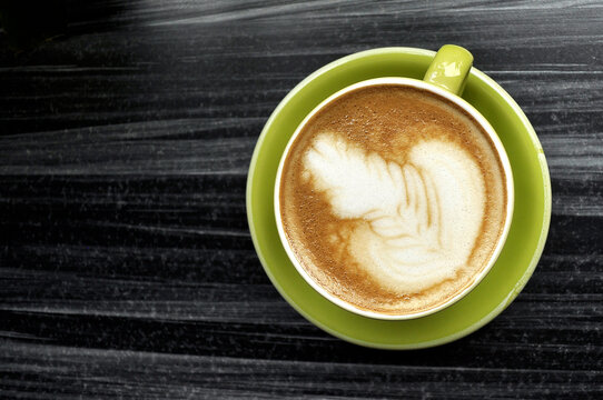 One Cups Of Coffee On Black Wooden Table Background With Beautiful Latte Art In Green Mug
