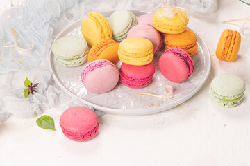 Colorful french macaroon cakes. Macaroons with jasmine flowers on white table background. Selective focus