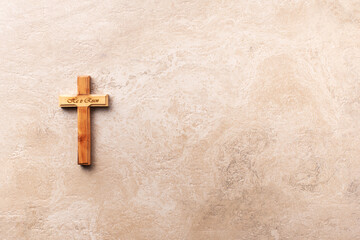 Wooden cross with text He is risen on marble background. Reminder of Jesus sacrifice and Christ resurrection. Easter passover. Palm sunday, Good friday concept. Christianity symbol and faith.