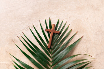 Palm Sunday concept. Wooden cross over palm leaves. Reminder of Jesus sacrifice and Christ...