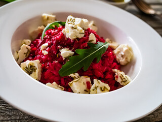 Risotto with beetroots and feta cheese on wooden table
