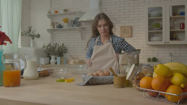 Woman in kitchen wearing apron. Female chef preparing cooking space for cooking food. Attractive girl wearing apron in modern cuisine. Beauty girl preparing for cooking food