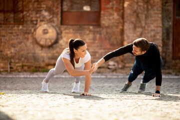 Young couple doung one arm pushup exercise in the urban environment
