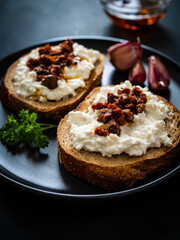 Breakfast - cottage cheese, bread, bruschetta and vegetables on black wooden table