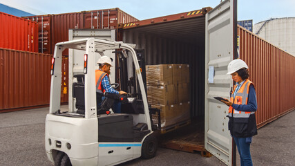 Forklift Driver Loading a Shipping Cargo Container with a Full Pallet with Boxes in Logistics Port...