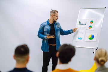 Male business coach speaker giving flipchart presentation, speaker leading consulting training...