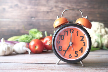 alarm clock and fresh vegetables on table with copy space