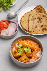 spicy gravy chicken served in a  bowl with butter naan