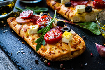Focaccia - roasted mozzarella sandwiches with salami pepperoni, feta cheese and tomatoes on black...