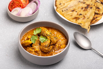 spicy gravy chicken served in a  bowl with butter naan