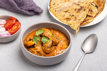 spicy gravy chicken served in a  bowl with butter naan