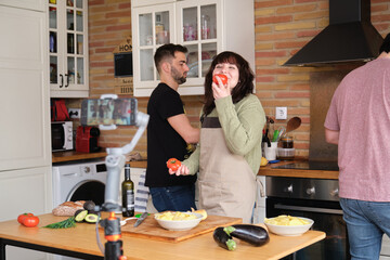 Young woman smelling a tomato and recording a video with her smartphone for her cooking channel. Content creator and influencer.