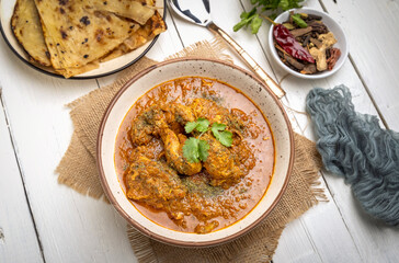 spicy gravy chicken served in a  bowl with butter naan