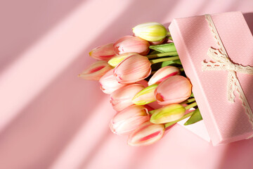 Bouquet of tender tulips and gift box isolated on pink background with shadow. Spring flowers. Greeting card for Birthday, Woman, Mother's Day, Wedding, Valentine's day. Flat lay. Copy space