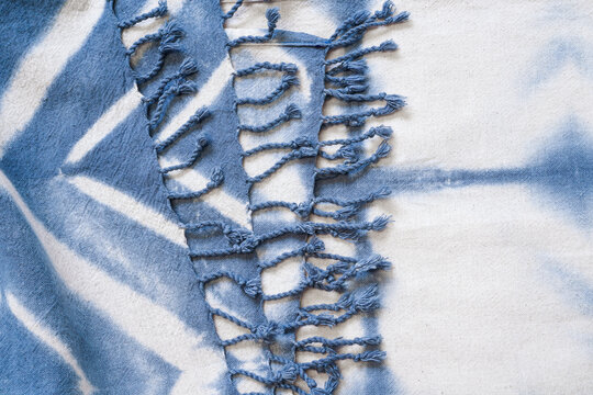 Layer of Natural tie dye cloth or fabric shawl in white and blue pattern with tassel or festoon