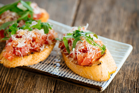 Salmon bruschettas with grated cheese and arugula on the wooden background