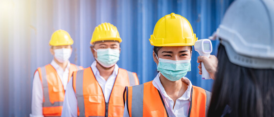 Engineers wearing face masks line up for temperature check before entering workplace.  Coronavirus pandemic. Social distancing.