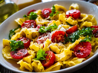 Tortellini stuffed with prosciutto ham and vegetables on wooden table
