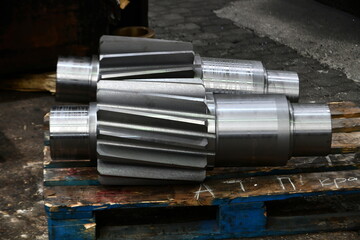 Gear shaft after heat treatment on a wooden rack.