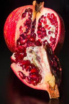 Pomegranate and segment against a black background