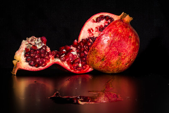 Pomegranate and segment against a black background