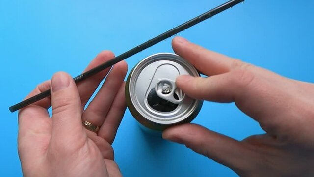 the man inserts a straw into a soda can