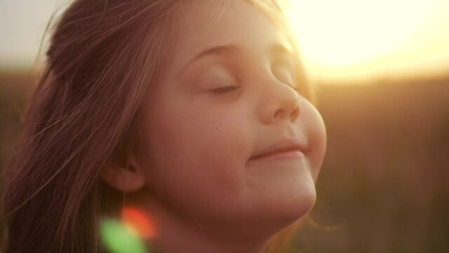 happy little girl child closed her eyes dreams. kid wants a dream come true portrait at sunset. baby daughter silhouette dreaming of a happy childhood. free face sister side lifestyle view thinks