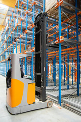 Interior view of a warehouse with racks, pallets, goods, forklifts