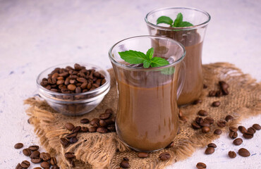 Two coffee mous dessert decorated with mint on a white background.
Close-up.