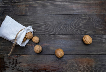 Canvas bag with walnuts on a wooden table. Wooden table with walnuts in a bag.