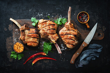 Grilled veal meat ribs cutlets with ingredients on rustic dark background - obrazy, fototapety, plakaty