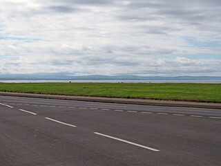 Fototapeta na wymiar The coast road at crosby in merseyside with grass surrounding the sea at the mouth of the river mersey