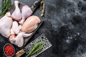 Fresh raw chicken meat, wings, breast, thigh and drumsticks. Black background. Top view. Copy space