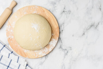 Yeast dough on a wooden board. Marble background. Culinary concept. Top view