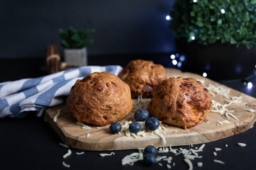 Blueberries, cotton cloth with blue and white stripes, crunchy crust of home baked flax flour bagels with mozzarella cheese, wooden board, selective focus, dark background. Natural light, fairy lights