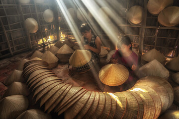 Two Vietnamese sisters craftsman making the traditional vietnam hat in the old traditional house in...