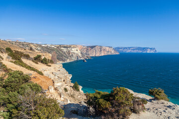 Fototapeta na wymiar View of the Black Sea coast in Crimea, Cape Fiolent in Sevastopol. Panoramic seascape, calm azure sea, clouds and bright sky.