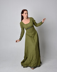 full length portrait of red haired girl wearing celtic, green medieval gown. Standing pose isolated against a studio background. © faestock