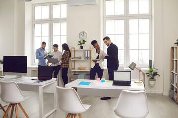 Business workflow, communication, conversation, team work concept. Group of multi-ethnic corporate employees working in co-working open space. Diverse young people with gadget cooperating on project