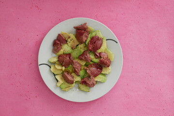Avocat et foie de poulet dans une assiette sur fond rose. Vue du dessus. Alimentation équilibrée