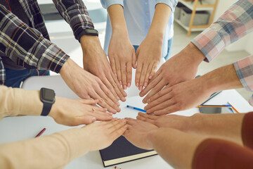 Group of high school, college or university students join hands in circle showing determination,...