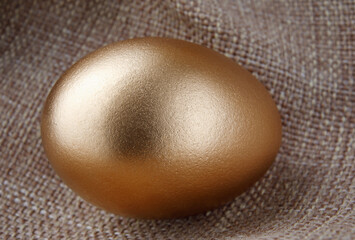 A golden egg on a fabric background.