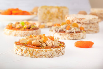 Puffed exploded wheat grains with peanuts and dried apricots on a thin layer of apricot jam on a background of oriental sweets on a white wooden table