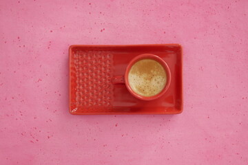 Café dans une tasse rouge sur fond rose, vue d'en haut. Composition coloré