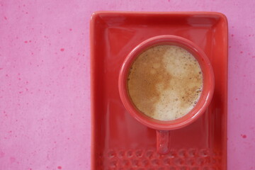 Café expresso dans une tasse rouge sur fond rose, en gros plan, vu d'en haut. Composition...