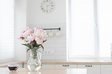 Bouquet of pink peonies and a cup of coffee. Modern interior in the kitchen. Wedding and festive style.