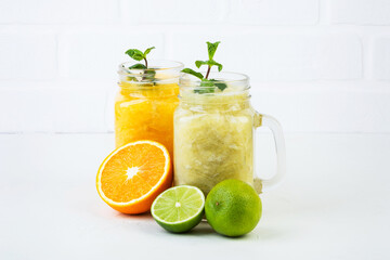 Orange and lime smoothie with mint in glass cups and halved fruit