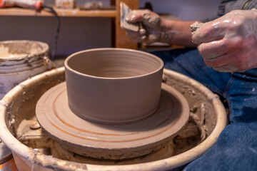 close up on male hands working on a potters wheel to make a bowl