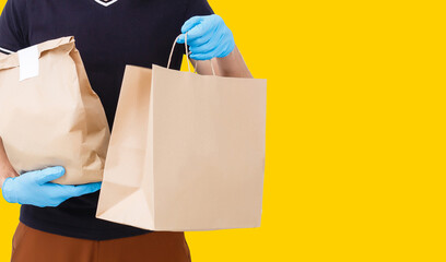 delivery man carrying paper bag with food products isolated over yellow background